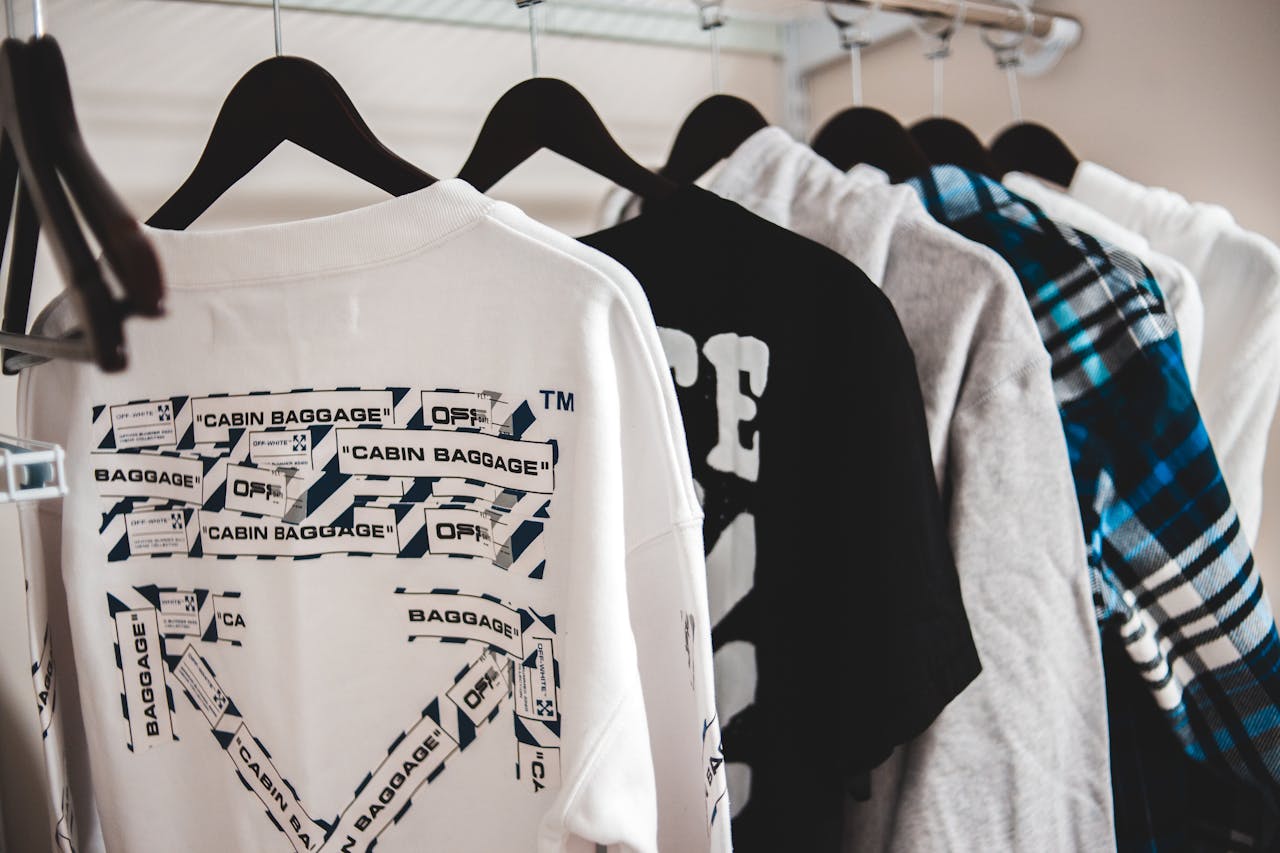 Assorted stylish male apparel hanging on plastic racks on metal beam in wardrobe